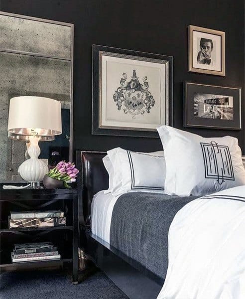 Classy black bedroom with framed wall art, mirrored nightstand, and elegant white bedding.