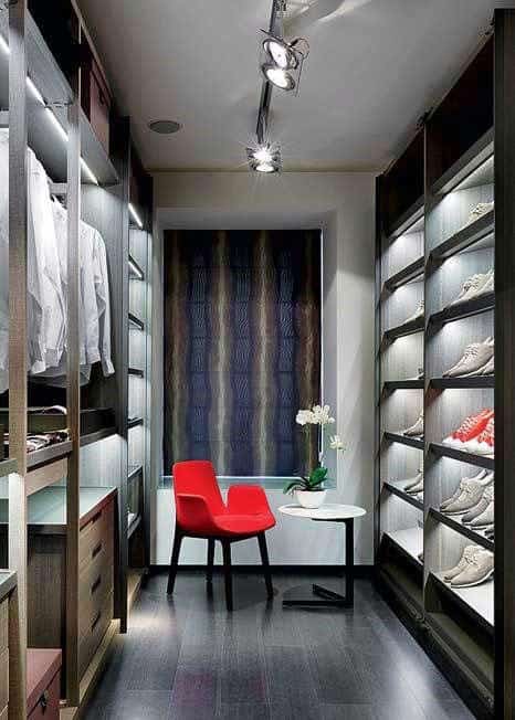 A modern walk-in closet with shelves, a red chair, and a small round table with a plant