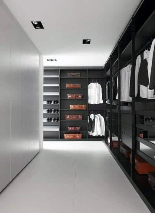 Spacious modern walk-in closet with black shelves, white shirts, and leather boxes neatly arranged