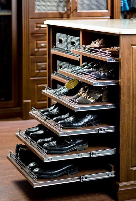 Pull-out wooden shelves with neatly organized men's shoes in a cabinet