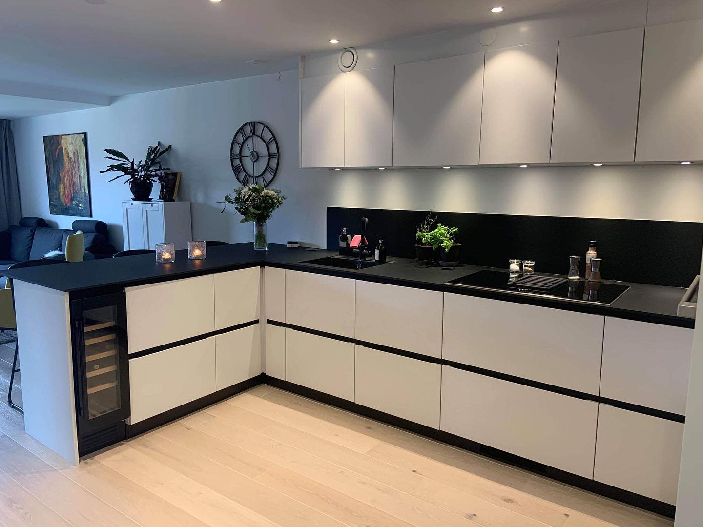 Contemporary white and black kitchen with built-in wine cooler and minimalist decor.