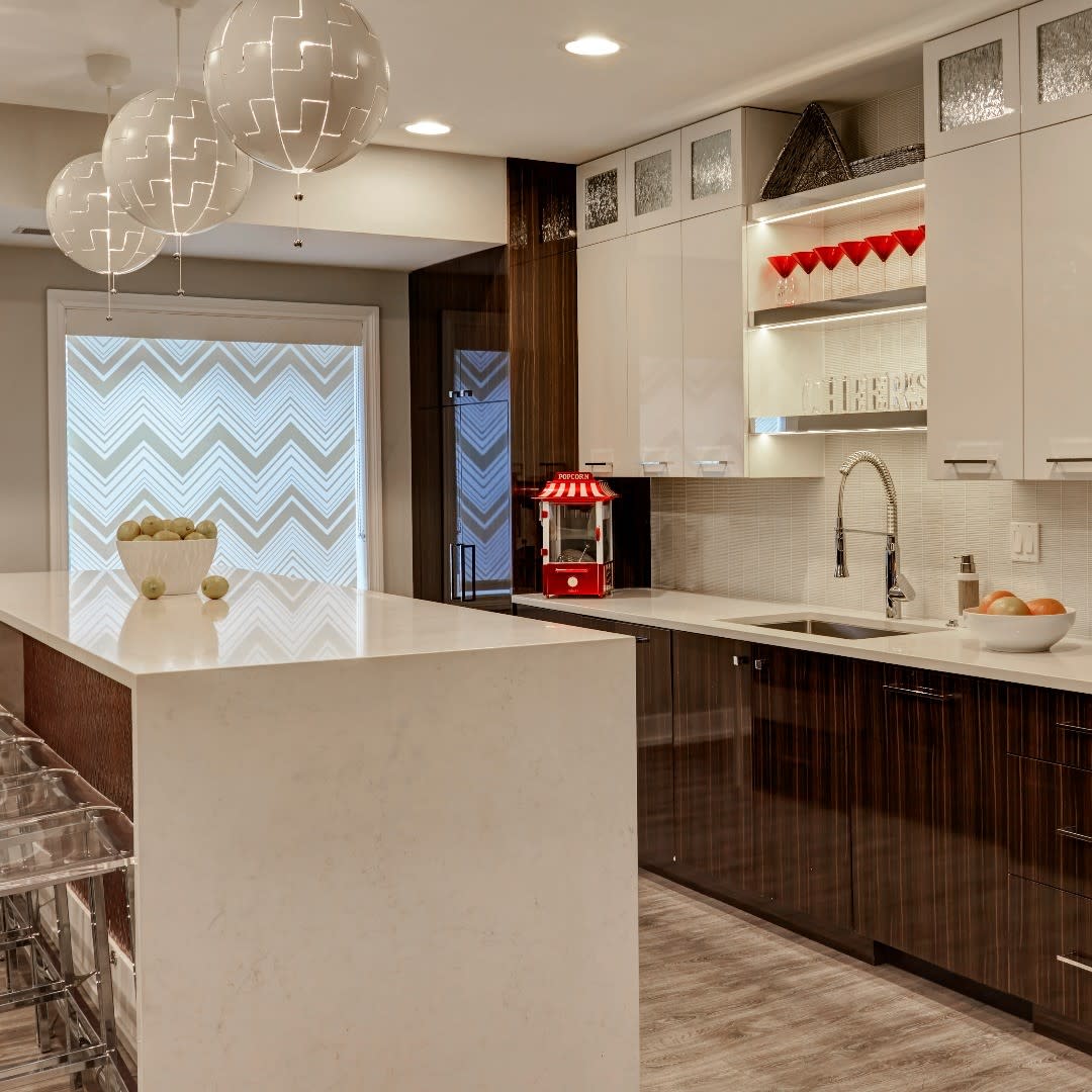 Contemporary kitchen with large white island, modern lighting, and sleek cabinetry.