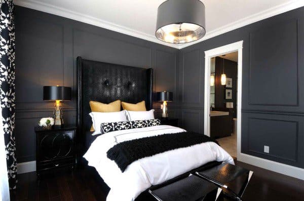 Chic black bedroom with paneled walls, gold accent pillows, and modern lighting fixtures.