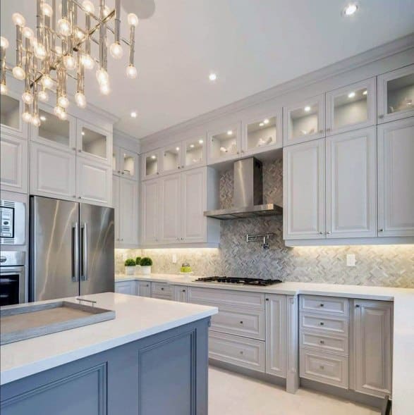 Modern kitchen with a statement chandelier above a marble island, sleek gray cabinetry, and stylish lighting