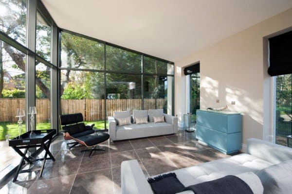 Bright sunroom with floor-to-ceiling glass windows and modern furniture.