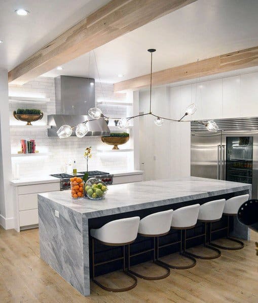 Contemporary kitchen with a sleek marble island, white bar stools, and unique glass and metal pendant lighting