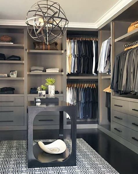 Modern walk-in closet with shelves of clothes, a central table, and a decorative ceiling fixture