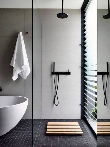 Minimalist modern bathroom with black fixtures, freestanding tub, and large window with louvered blinds.