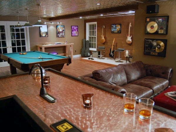 Music-themed mancave with pool table, cozy leather sofa, guitars on display, and copper bar counter.