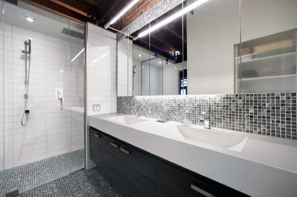 Bathroom with black and grey mosaic tile backsplash, double sink vanity, and glass shower.