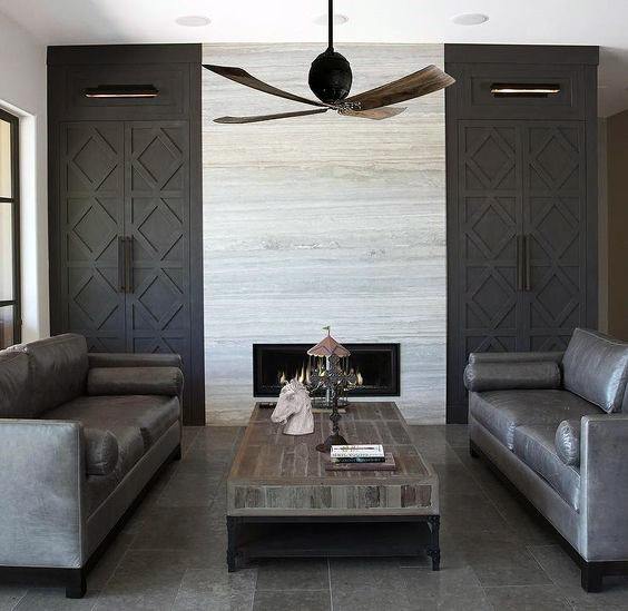 Modern living room with a linear fireplace, light stone tile surround, and dark gray built-ins.