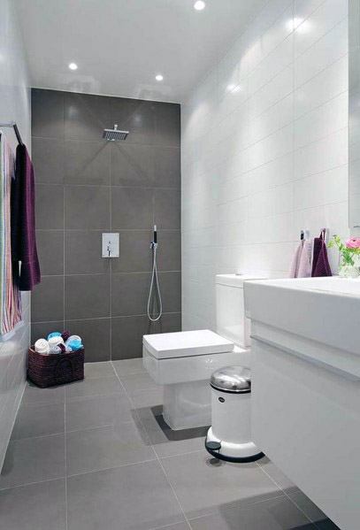 Modern bathroom with grey tiles, rainfall shower, white fixtures, basket, and towels