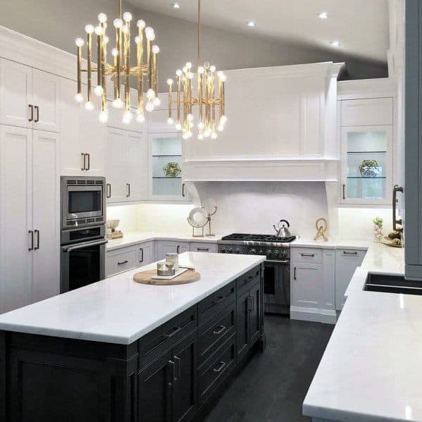 Modern kitchen featuring elegant gold pendant lights above a sleek black and white marble island with high-end appliances