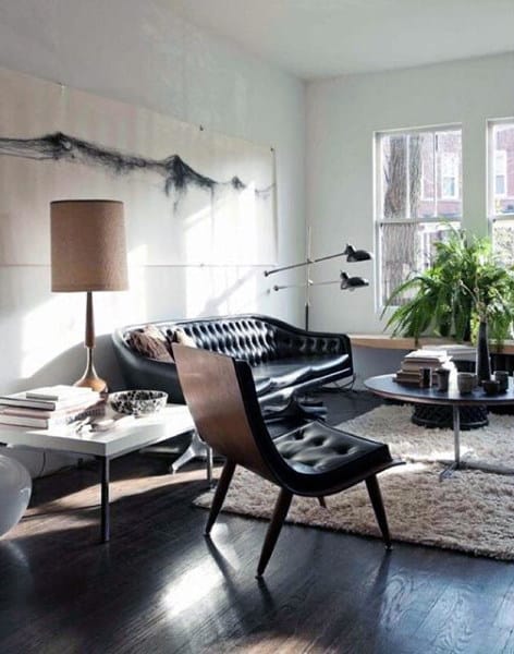 Living room with a black leather sofa, modern chair, and large windows bringing in natural light.`