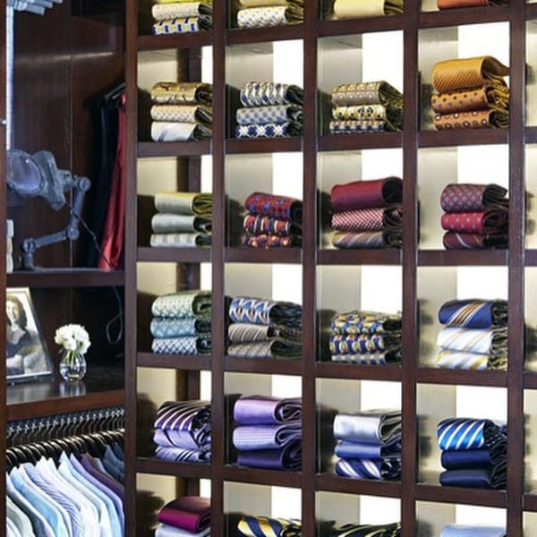 A wooden display shelf with neatly arranged folded ties of various colors and patterns