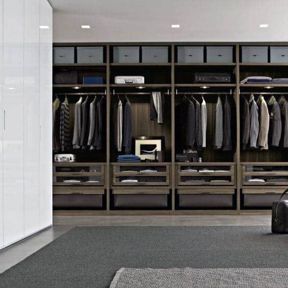 Modern, organized walk-in closet with neatly arranged clothes, drawers, and shelves in a black and white color scheme