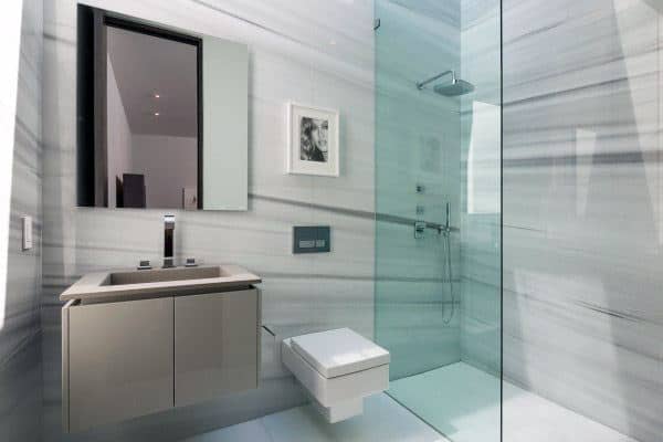 Modern bathroom with a sleek glass shower, wall-mounted toilet, and a chic vanity featuring a mirror cabinet