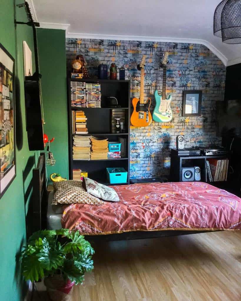 Teen bedroom with graffiti wallpaper hanging guitars black bookshelf and vibrant bedding.