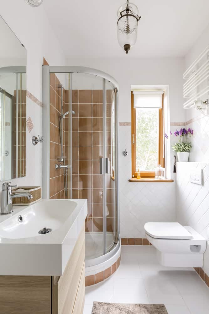 Bright bathroom with corner shower, brown tiles, modern sink, and natural light.