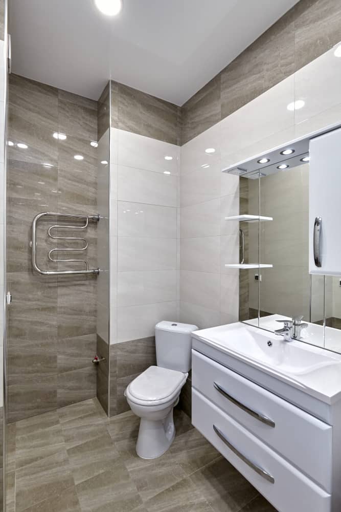 Modern bathroom with beige tiles, white vanity, and heated towel rack.