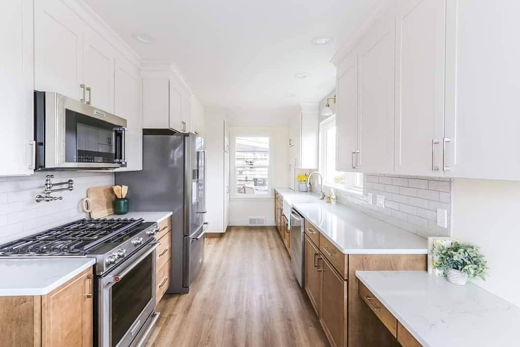 long galley kitchen white and natural wood cabinets white tile backsplash 