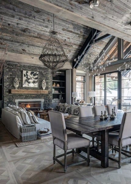 A creative rustic living room featuring a stone fireplace, a large dining table, and an elegant mix of wood and modern lighting for a cozy yet stylish atmosphere.