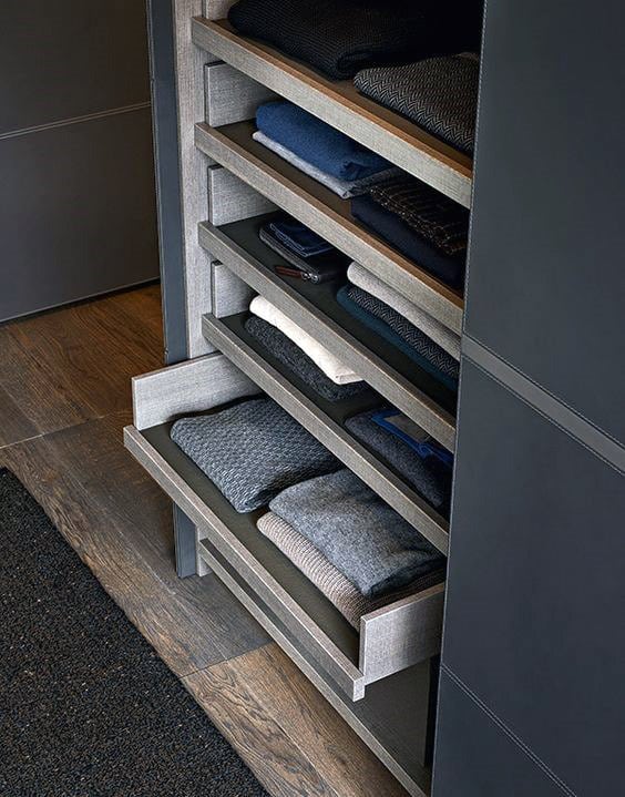 Open closet with neatly folded clothes on pull-out shelves