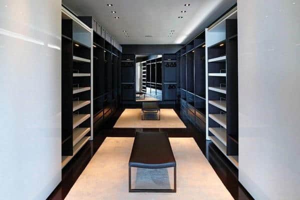 Minimalist walk-in closet with black shelves, mirrored back wall, and a central bench