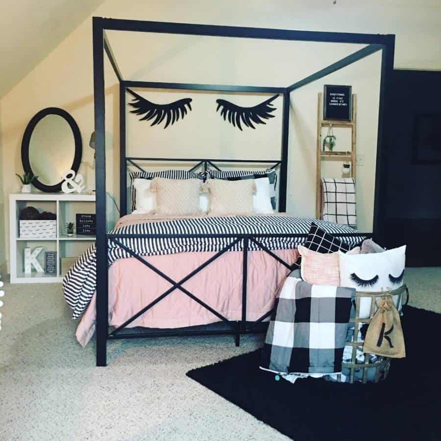 Teen bedroom with metal four-poster bed, eyelash wall decor, and cozy pillows.