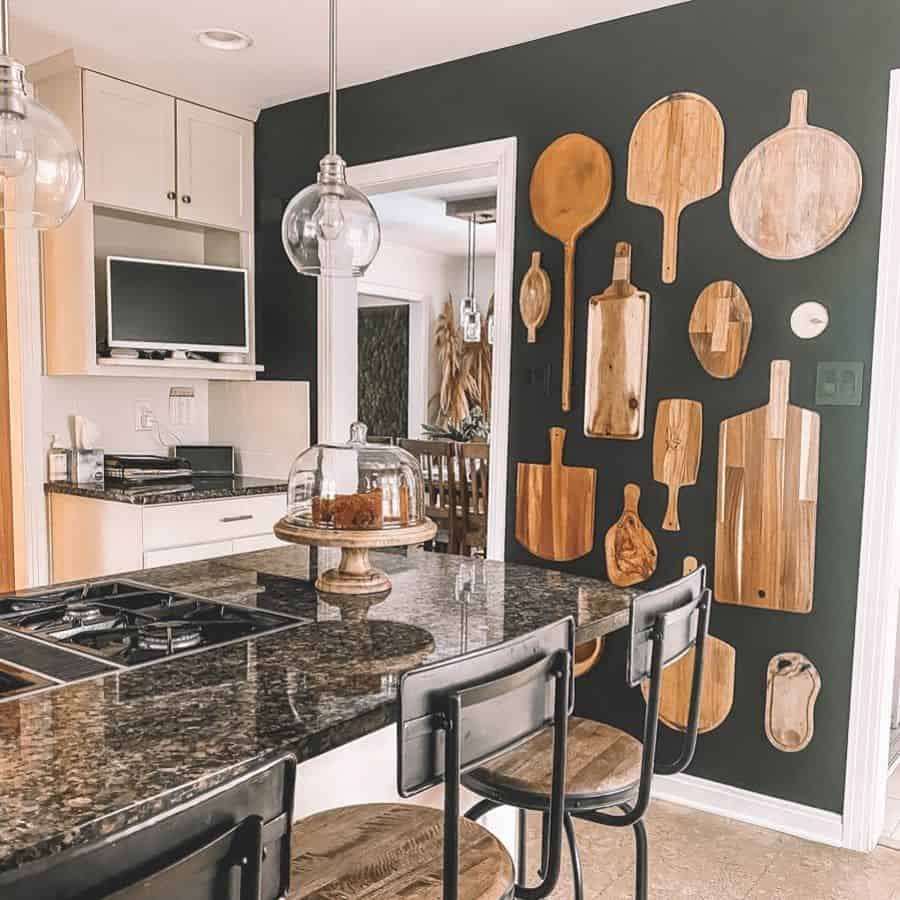 Decorative cutting boards displayed on a black wall with a granite kitchen island.