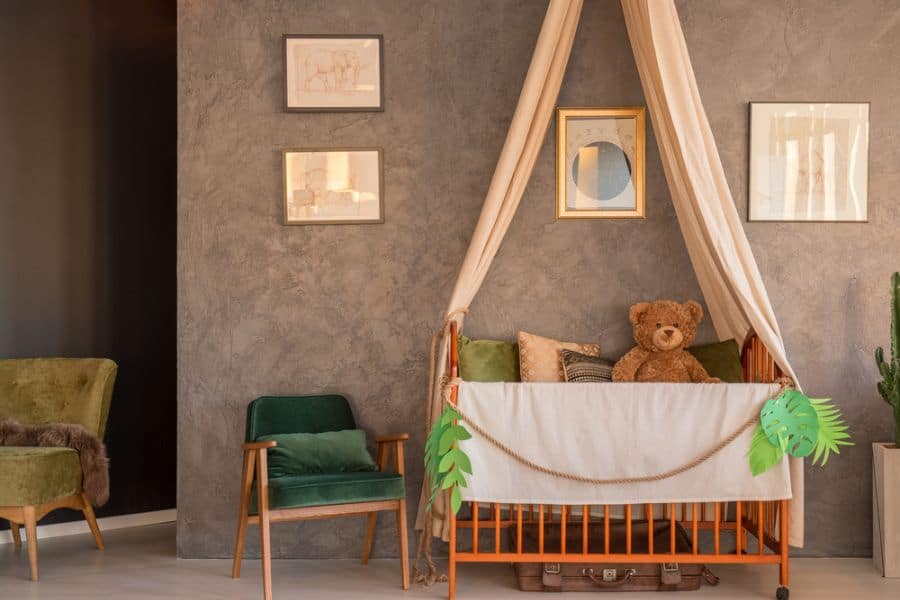 Cozy baby room with burnt orange crib, canopy, earthy tones, and velvet green chairs for a warm, vintage feel.