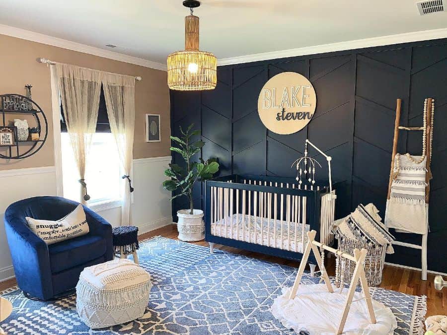 Dark baby room with black accent wall, white crib, navy armchair, and personalized wall decor with modern boho touches.