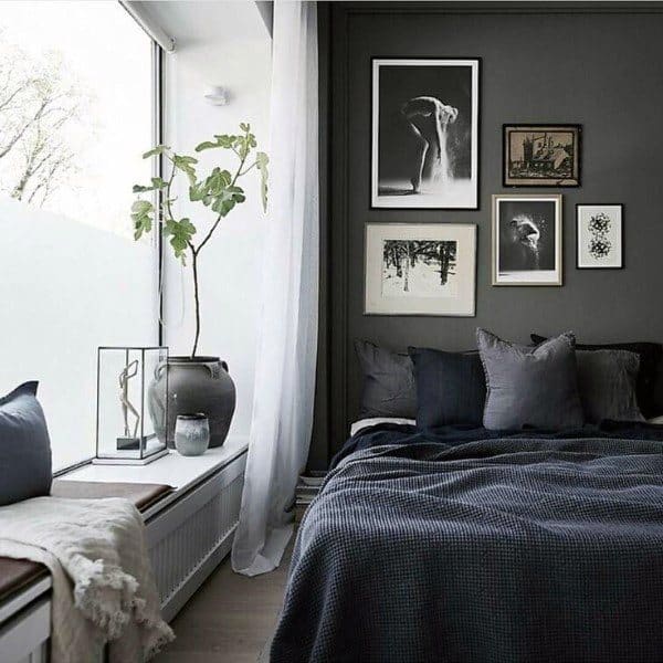 Cozy black bedroom with gallery wall, sheer curtains, and natural light from large windows.