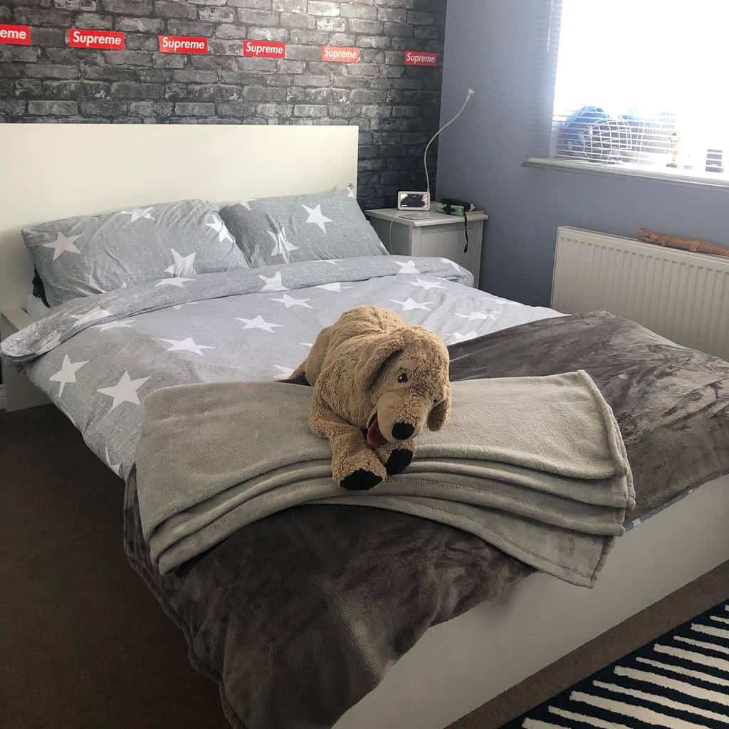 Kids' bedroom with fake brick wall, Supreme stickers, gray bedding, and plush dog toy.