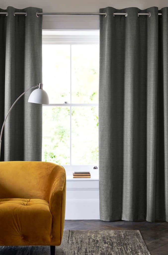 dark gray curtains in living room with yellow accent chair 