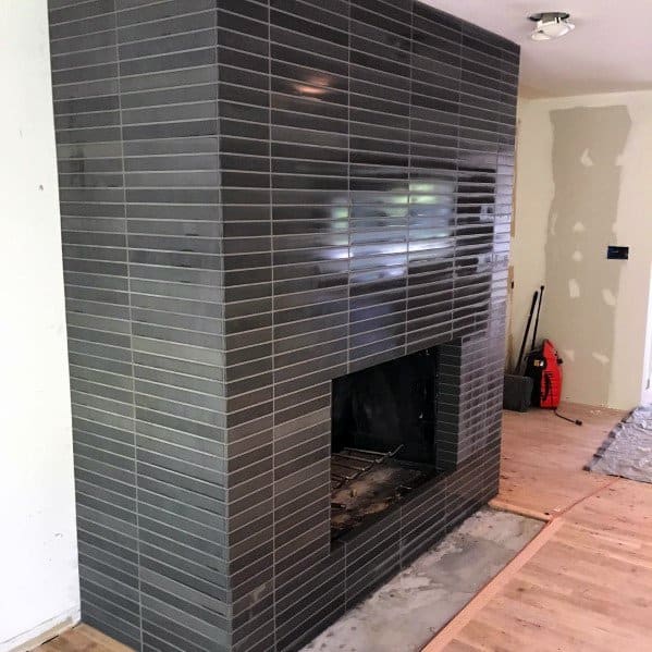 Contemporary fireplace with glossy dark gray subway tiles and a minimalist design.