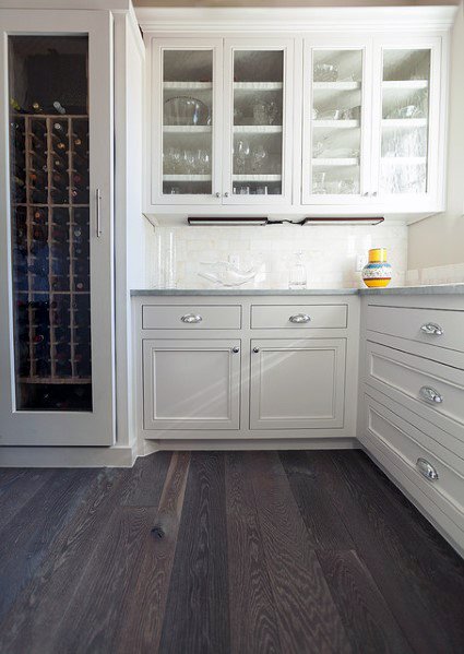 Elegant kitchen with dark hardwood flooring, white cabinetry, and a wine storage area, creating a clean and sophisticated space