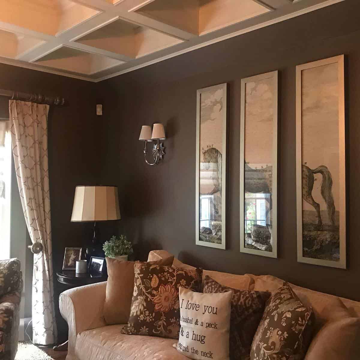 Cozy living room with a beige sofa, brown-patterned cushions, framed art, and a lamp on a side table