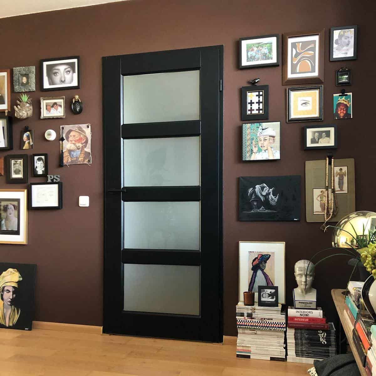 Brown-framed artworks adorn the wall, complementing the black door with frosted glass panels