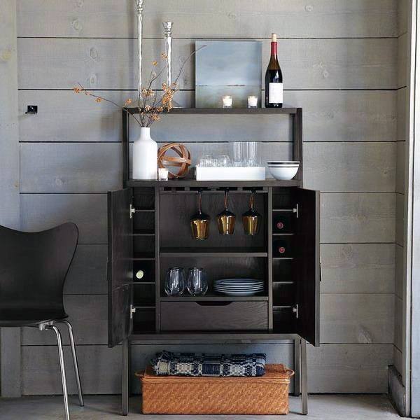 Compact dark wood mini bar with glassware, wine storage, and modern rustic decor accents.