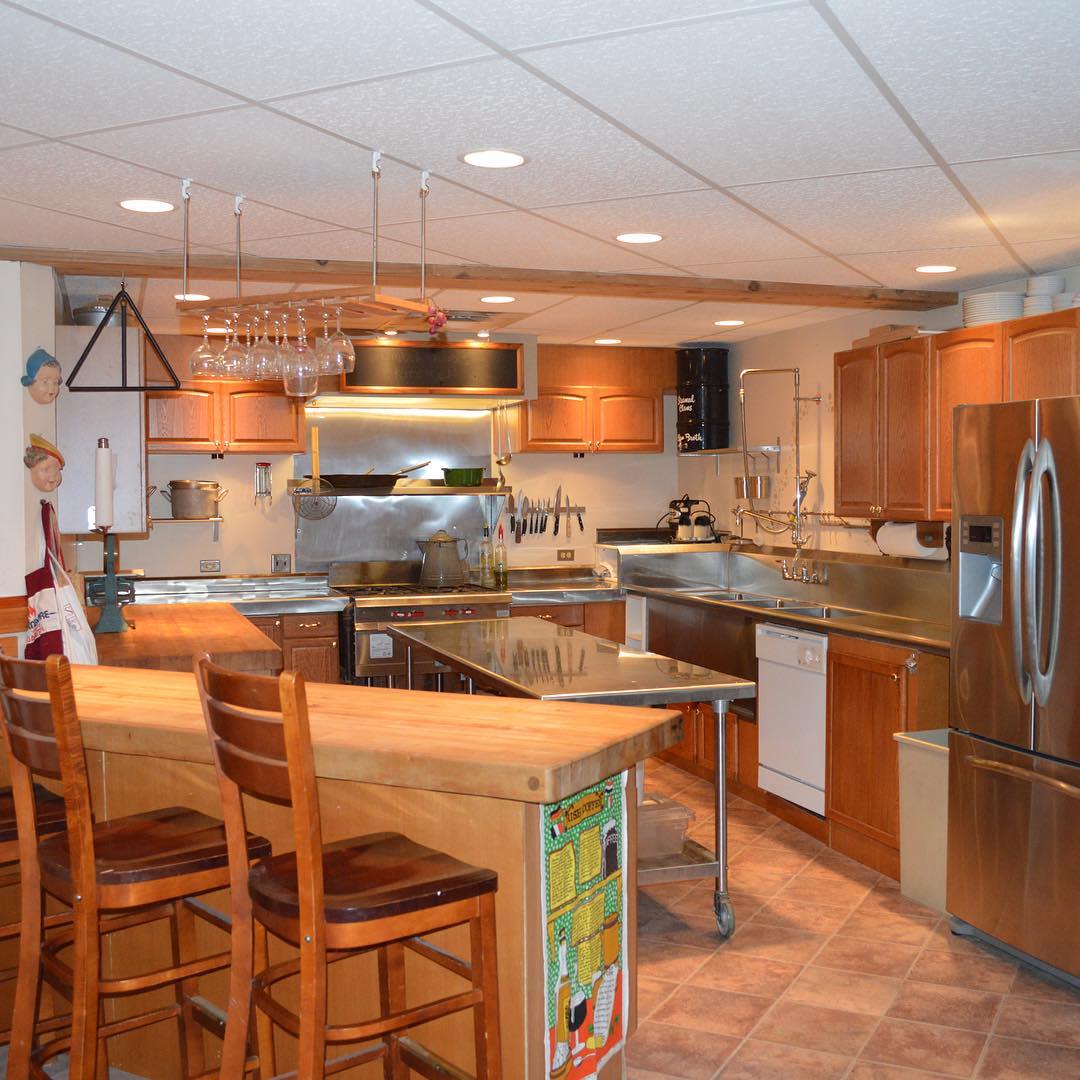 Large kitchen with wood cabinets, metal countertops, and a breakfast bar with stools.