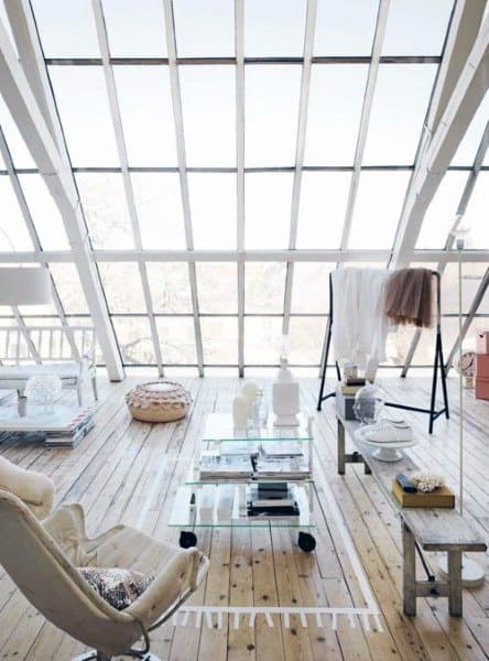 Minimalist sunroom with a sloped glass ceiling, natural wood flooring, and modern furniture for an airy, open feel.