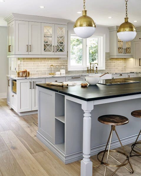 Charming kitchen with light hardwood flooring, grey cabinetry, a black countertop island, and stylish gold pendant lighting