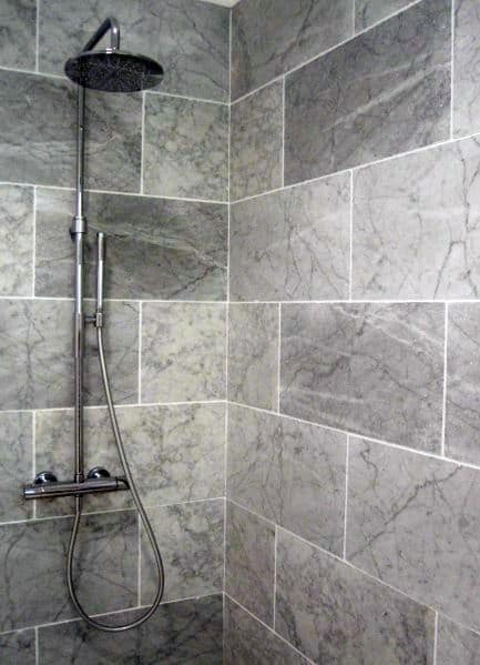 A modern shower with grey stone tiles and a rain showerhead