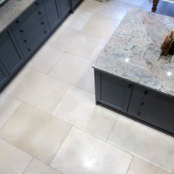 Elegant kitchen with large-format beige tile flooring, grey cabinetry, and a granite countertop island