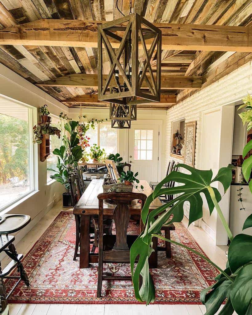 Rustic dining sunroom with a wooden table, antique chairs, and a red patterned rug.