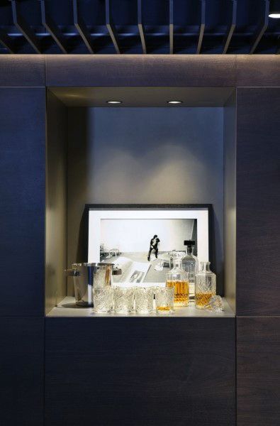 Sleek mini bar with glass decanters, crystal glasses, and modern backlit shelving display.