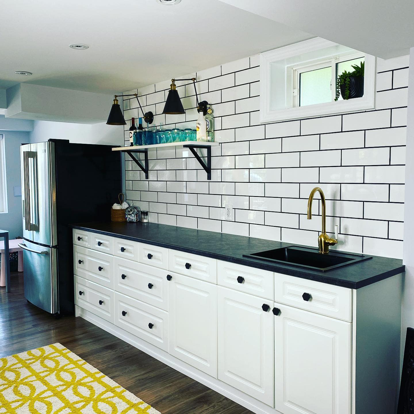 Modern kitchen with white cabinets, black countertops, and subway tile backsplash.