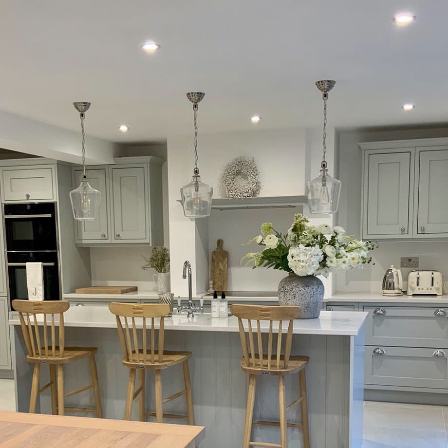 Modern kitchen with grey cabinets, island seating, pendant lights, and floral centerpiece.