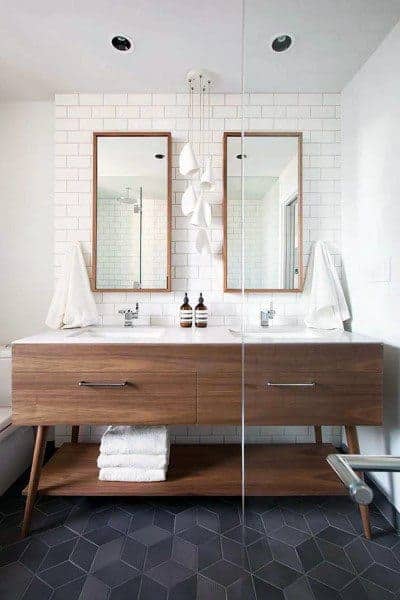 Bathroom with wooden double vanity, white subway tile wall, and geometric tile floor.